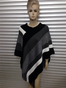 Macro detail of V-neck striped knit poncho showing fringe hem and soft woven fabric texture