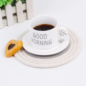 Close-up of woven cotton heat-resistant coasters with white Good Morning ceramic cup
