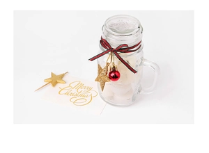 Close-up of glass mason jar with red and green striped ribbon and Christmas ornaments