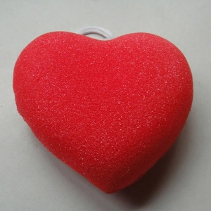 Macro detail of a red heart-shaped bath sponge with a white hanging loop for drying