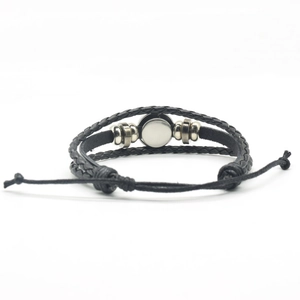Detailed view of black braided leather bracelet with silver metal charms and drawstring
