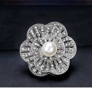 Detail of silver floral brooch with clear crystals and a large white pearl center