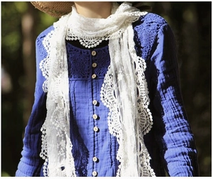 Detailed view of white floral lace scarf featuring intricate hollow patterns and wavy edges