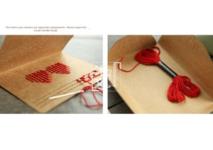 Detail of DIY kraft paper heart cross stitch card kit with red embroidery thread and needle
