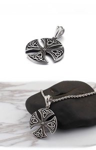 Macro detail of retro stainless steel Celtic cross pendant with knot relief and rope chain