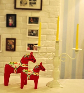 Nordic red Dala horses and white metal candelabra on a shelf for cozy home decor