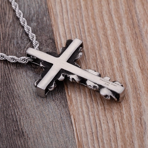 Stainless steel 316L cross pendant necklace with a silver twist chain on a wooden base