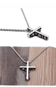 Macro detail of stainless steel cross pendant with skull carvings and twisted rope chain