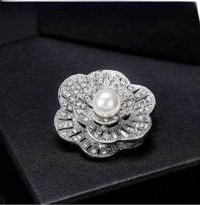 Macro shot of a silver flower brooch with pave-set rhinestones and a central pearl detail