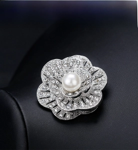 Detail of silver camellia brooch with white pearl and rhinestones on black display