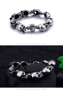 Detail shot of punk skull link bracelet in titanium steel on black textured stone surface
