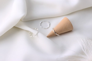 Macro view of three S925 sterling silver minimalist rings on elegant white silk fabric