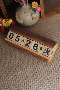 Détail d'un calendrier perpétuel en bois avec écorce naturelle et blocs de date mobiles