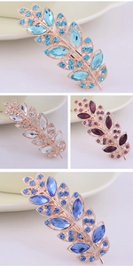 Close-up of leaf-shaped hair clips with sparkling rhinestones in multiple colors