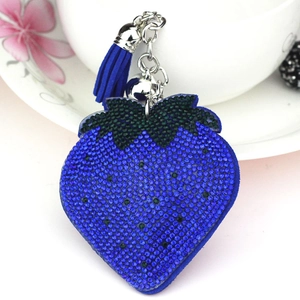 Close-up of blue strawberry rhinestone keychain with silver bell and blue tassel