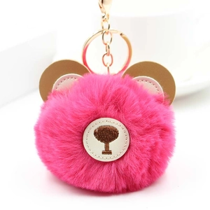 Close-up of fluffy pink faux fur bear keychain with gold clasp and leather ears