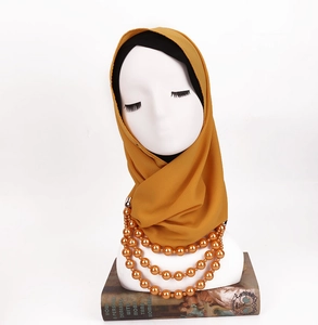 Detail of ginger ethnic scarf with multilayered gold beads on white mannequin
