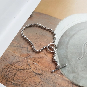 Macro detail of silver beaded bracelet featuring a minimalist toggle clasp closure