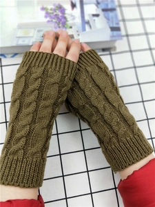 Detail of dark olive green cable knit fingerless gloves showing thick woolen texture