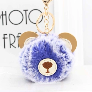 Detail of blue and white plush ball keychain with brown leather ears and gold metal clip