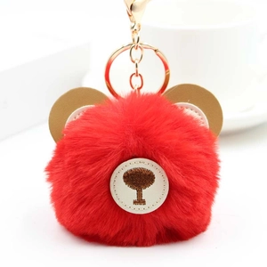 Detailed view of red plush bear keychain with golden metal ring and brown ear accents