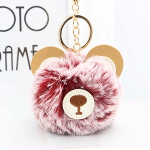 Close-up of fluffy burgundy bear keychain with faux fur, leather ears and golden metal ring