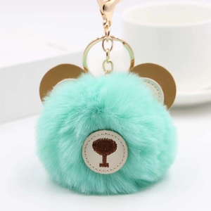 Detail of mint green fluffy pom pom keychain with brown bear ears and golden clasp