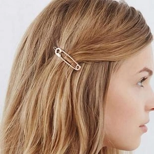 Detail of a minimalist rose gold safety pin hair clip worn by a model in brown hair