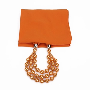 Detail eines orangen Chiffon-Schals mit goldener Perlenkette und Metallverschluss
