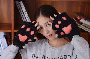 Close-up of black plush cat paw fingerless gloves with pink paw pads worn by a model