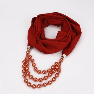 Detail eines roten Chiffonschals mit dreilagigen Perlen und elegantem Metallverschluss