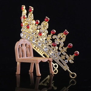 Macro detail of luxurious gold bridal tiara with red and clear rhinestones on chair