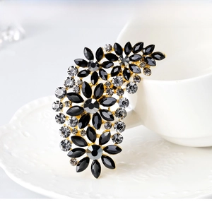 Detailed shot of a black and clear crystal flower brooch on a white decorative plate