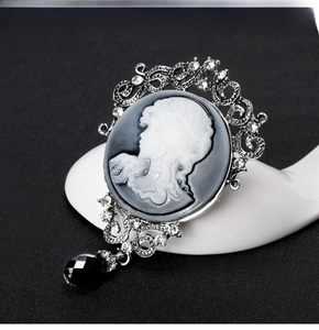 Detail of vintage silver relief brooch featuring a girl portrait and black faceted bead