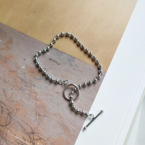 Detailed close-up of a silver bead bracelet with a classic T-bar toggle clasp on a magazine