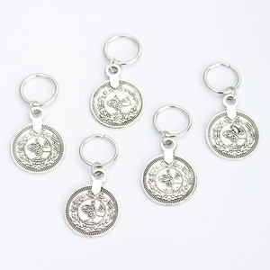 Close-up of five silver coin charms with intricate totems for DIY jewelry making