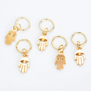Detail shot of five golden alloy Hamsa hand charms with jump rings for jewelry styling