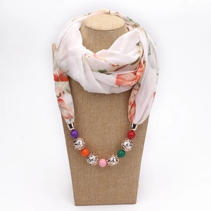 Detail of floral chiffon necklace scarf with colorful beads on a beige mannequin