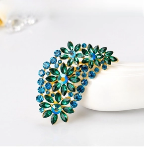 Detail view of emerald and blue crystal floral brooch with golden alloy setting