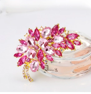 Close-up of pink crystal flower brooch with gold alloy frame and marquise stones