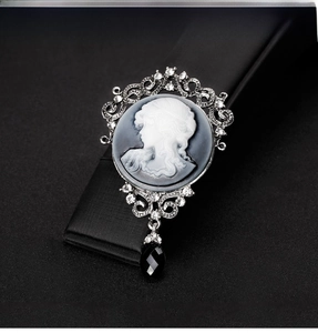 Macro shot of silver vintage cameo brooch with lady portrait and black crystal drop