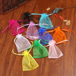 Macro detail of assorted colorful organza drawstring gift bags on a rustic wood background