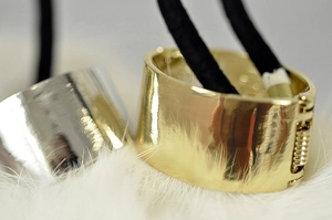 Polished gold and silver alloy ponytail cuffs on soft white fur backdrop for women