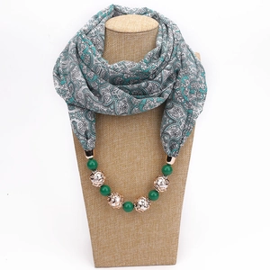 Detail of turquoise chiffon scarf with beaded necklace and elegant white pattern