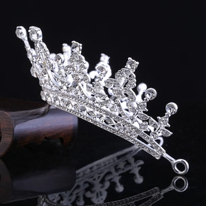 Macro shot of silver bridal crown with crystals on a dark wood base and black background