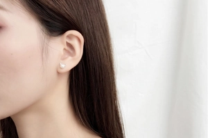 Close-up of minimalist cat ear pearl stud earrings worn, showing silver detail and luster