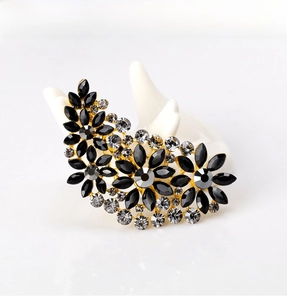 Detailed close-up of a floral crystal brooch with black and clear rhinestones on gold metal