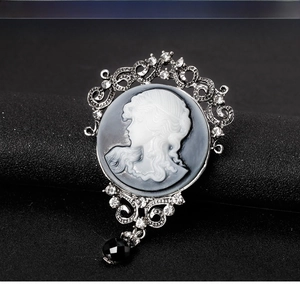 Detail view of retro cameo brooch with baroque crystal patterns and a black faceted drop