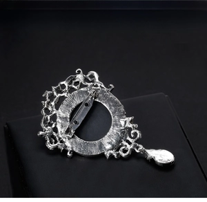Macro detail of vintage silver brooch back featuring safety pin and filigree patterns