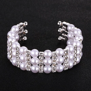 Macro view of a three-row pearl and rhinestone stretch bracelet with silver-tone metal accents